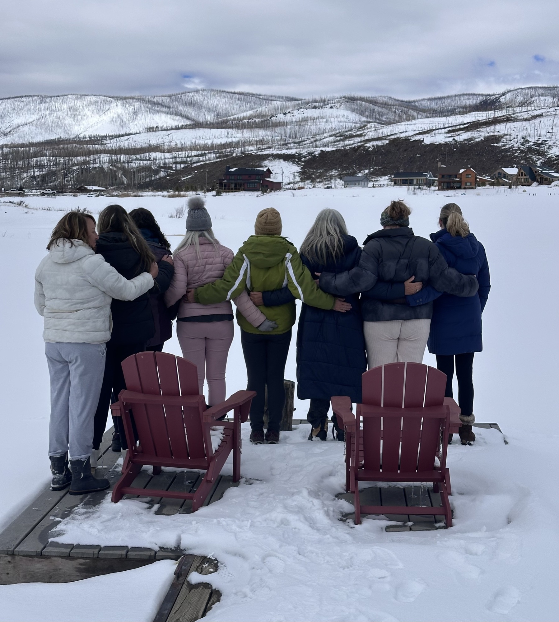 Group of women linked arm-in-arm overlooking snowy Colorado mountains